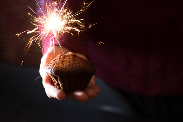 istock guy in a sweater holding a chocolate muffin with a burning sparkler 1086053920