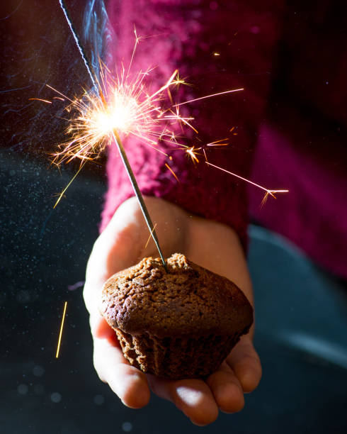 istock guy in a sweater holding a chocolate muffin with a burning sparkler 1086053922