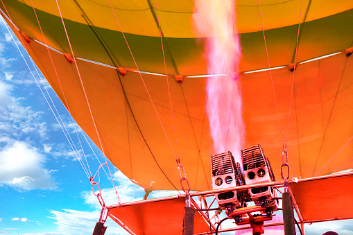 The flame of a powerful gas burner heats up, becomes fiery coral in color and fills the balloon balloon with hot air