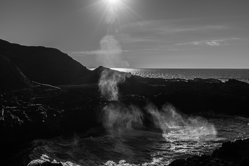 Backlight of the water expelled by a hole in the rock when the waves break in the Spouting Horn, Oregon, USA