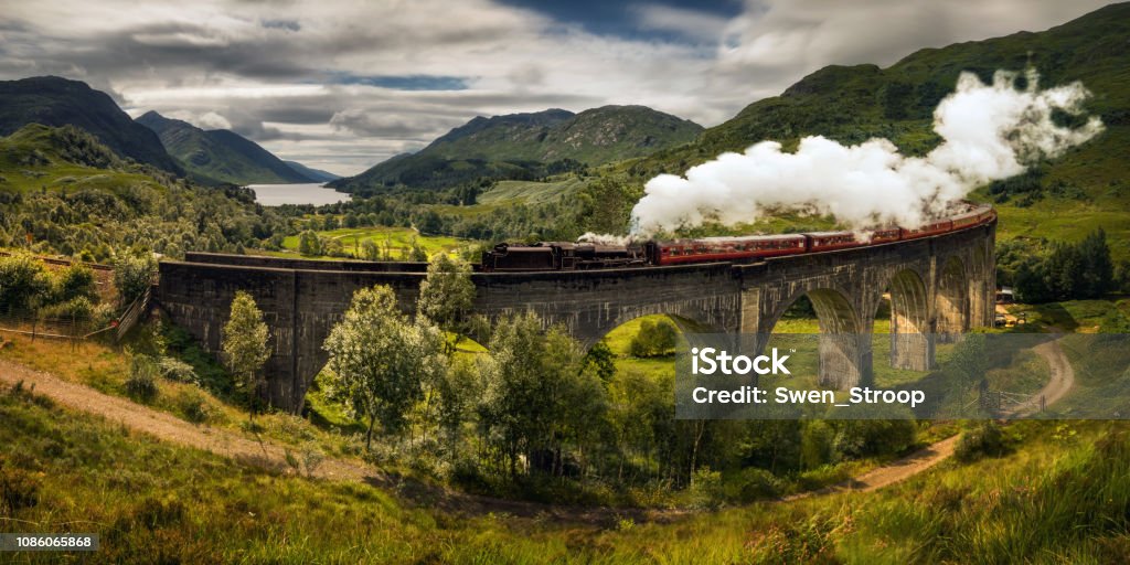 Steam train Jacobite Panorama of Jacobite steam train on old bridge, Scotland Hogwarts School of Witchcraft and Wizardry Stock Photo