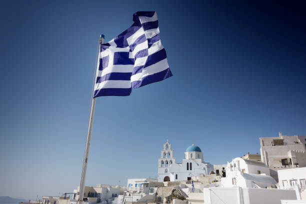 griechische flagge mit klassischer stadt oia und orthodoxer kirche, insel santorini, griechenland - hat oia europe vacations stock-fotos und bilder