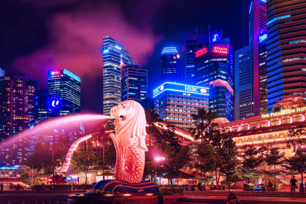 Skyscrapers Merlion statue at Merlion Park at night Singapore, Singapore - March 1, 2016: Merlion statue sprays the water from its mouth at Merlion Park in Downtown Core of Singapore at Marina Bay at night. Skyline with Skyscrapers on background singapore city stock pictures, royalty-free photos & images