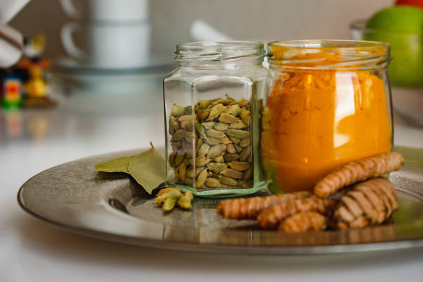 colorful indian spices turmeric and cardamom in a glass jar and mortar for spices close up. - cardamom cinnamon mortar and pestle herb imagens e fotografias de stock