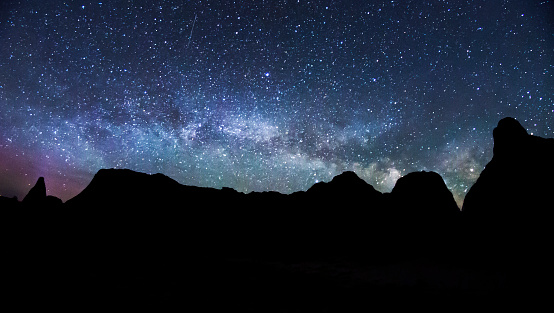 A landscape view of the Milky Way rising over a silhouette of the buttes in Badlands National Park in South Dakota.