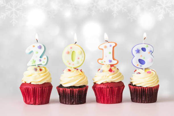 istock 2018 Happy New Year Cupcakes with candle lit light isolated with clipping path on winter silver white glittering light and pastel pink table background 1086130538