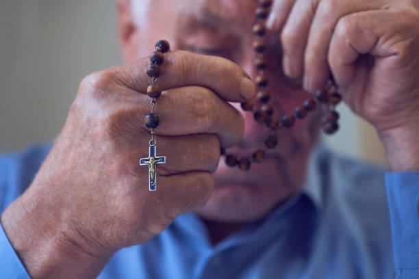 istock Praying hands of an old man holding rosary beads. 1086131248