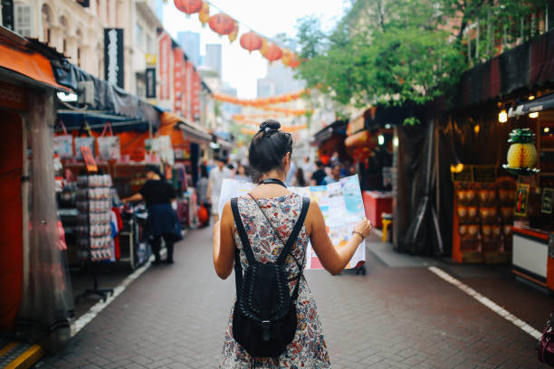 jonge solo reiziger vrouw in singapore street markt controleren van de kaart - travel stockfoto's en -beelden