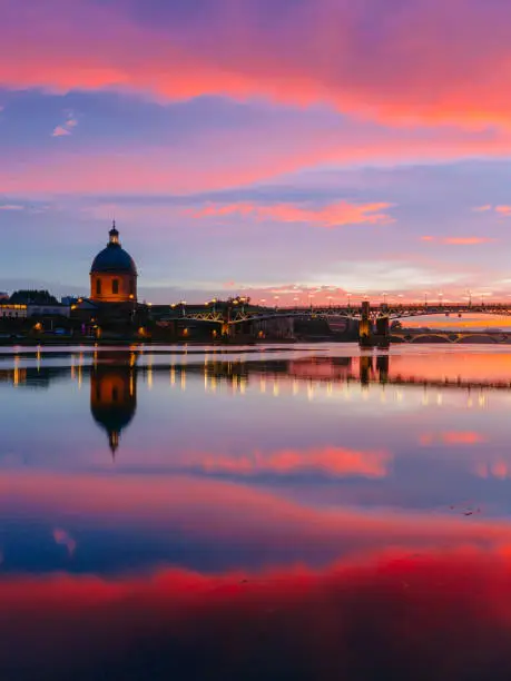 Pink and blue sunset over Garonne River, with reflections of Saint-Pierre Bridge and Chapel of hÃ´pital Saint-Joseph de la Grave, in Toulouse, France