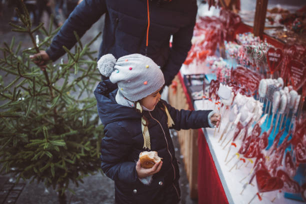 Young father with daughter on Christmas market. They walking around and picking what to buy.