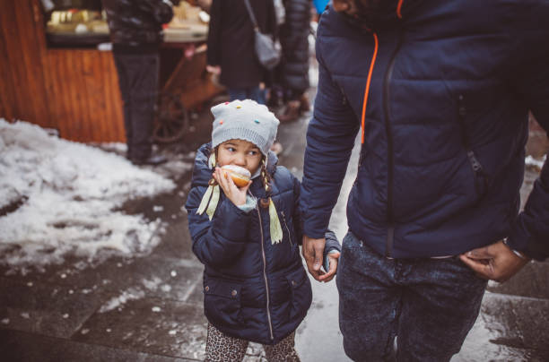 Young father with daughter on Christmas market. They walking around and picking what to buy.