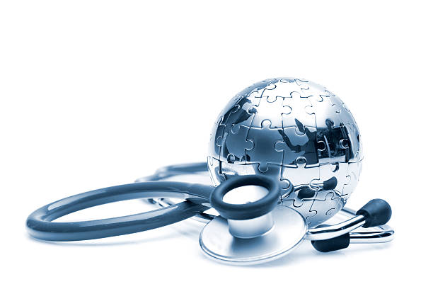 Stethoscope laying next to silver ball made of puzzle pieces stock photo