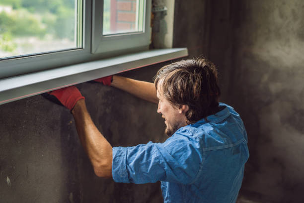 istock Man in a blue shirt does window installation 1086178744