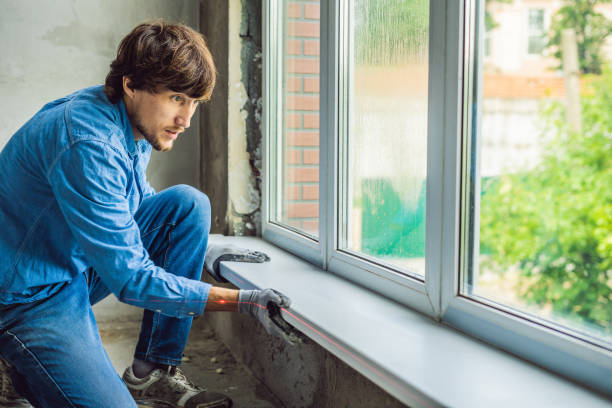 istock Man in a blue shirt does window installation 1086180968