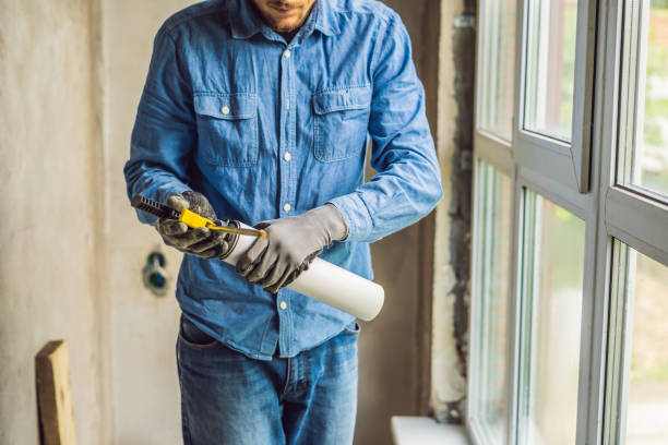 istock Man in a blue shirt does window installation. Using a mounting foam 1086181062