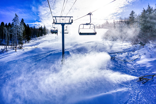 Skiers Riding Chairlift with Snowmaking