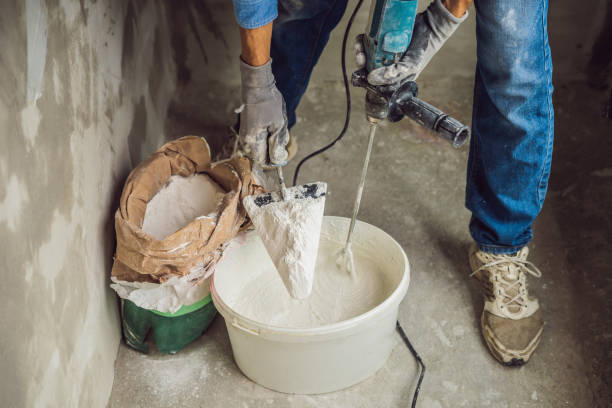 istock Young male painter kneads putty with water in a bucket using a hand-held mixer for building mixes 1086182952