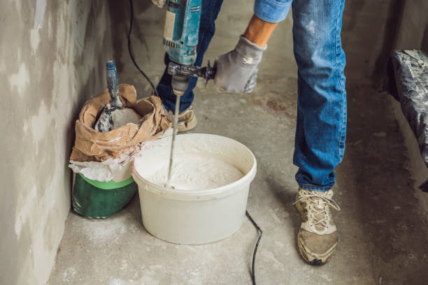 istock Young male painter kneads putty with water in a bucket using a hand-held mixer for building mixes 1086182954