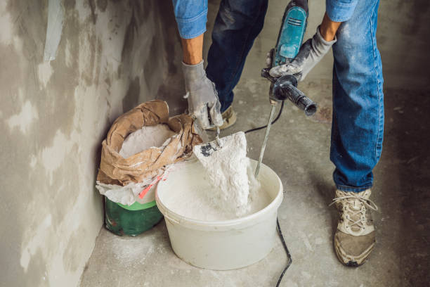 istock Young male painter kneads putty with water in a bucket using a hand-held mixer for building mixes 1086182962