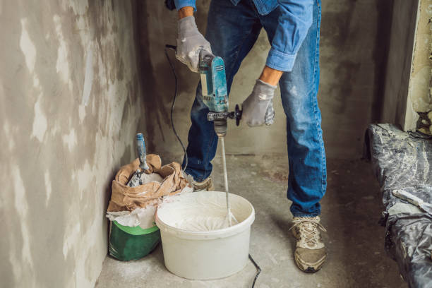 istock Young male painter kneads putty with water in a bucket using a hand-held mixer for building mixes 1086182966