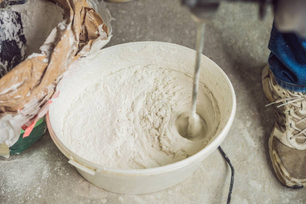 istock Young male painter kneads putty with water in a bucket using a hand-held mixer for building mixes 1086182968