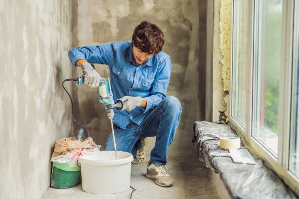 istock Young male painter kneads putty with water in a bucket using a hand-held mixer for building mixes 1086182972