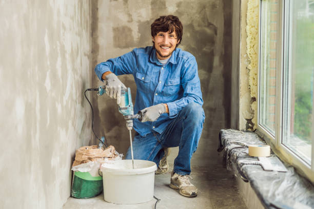 istock Young male painter kneads putty with water in a bucket using a hand-held mixer for building mixes 1086182974