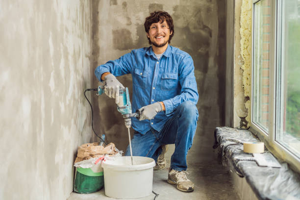istock Young male painter kneads putty with water in a bucket using a hand-held mixer for building mixes 1086182976