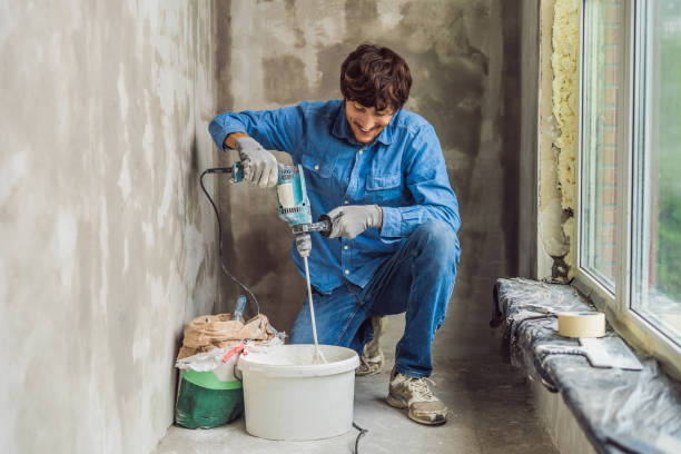 istock Young male painter kneads putty with water in a bucket using a hand-held mixer for building mixes 1086182998