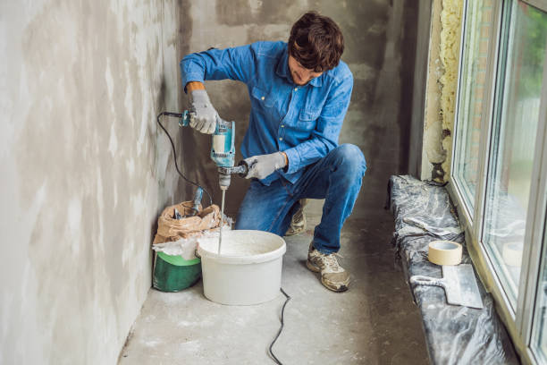istock Young male painter kneads putty with water in a bucket using a hand-held mixer for building mixes 1086183000