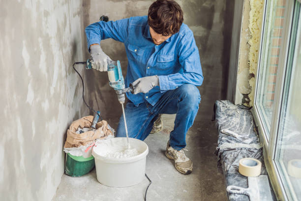 istock Young male painter kneads putty with water in a bucket using a hand-held mixer for building mixes 1086183006