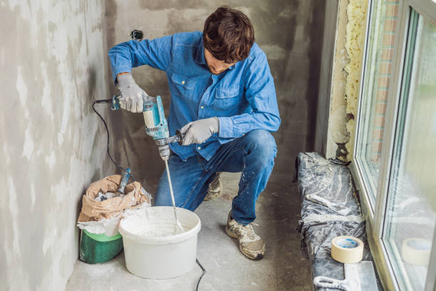 istock Young male painter kneads putty with water in a bucket using a hand-held mixer for building mixes 1086183010