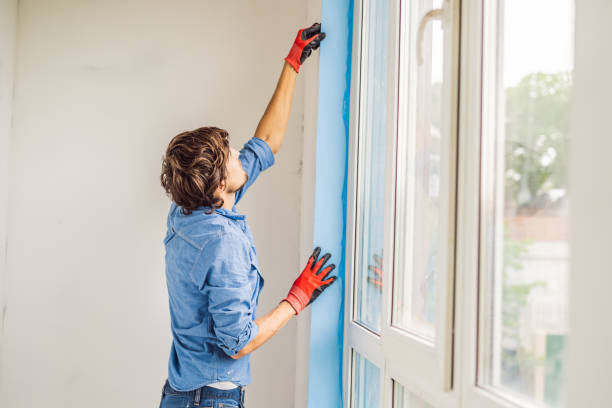 istock Man in a blue shirt does window installation 1086184620
