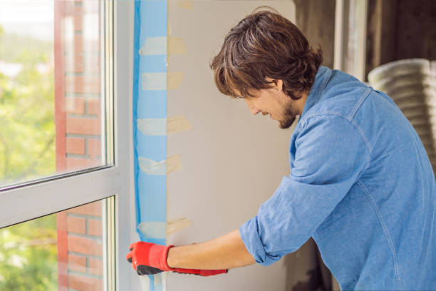 istock Man in a blue shirt does window installation 1086186478