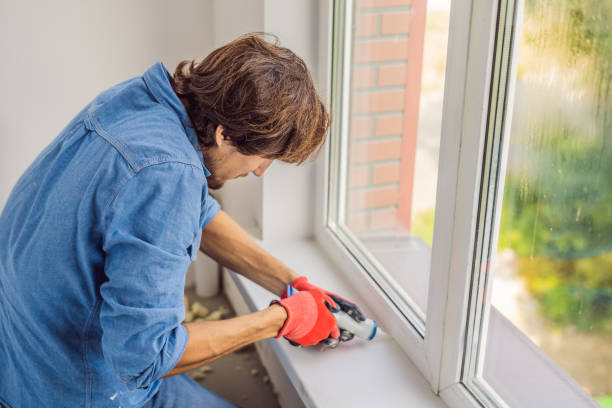 istock Man in a blue shirt does window installation 1086186514