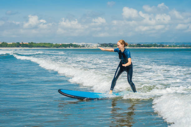 Joyful young woman beginner surfer with blue surf has fun on small sea waves. Active family lifestyle, people outdoor water sport lesson and swimming activity on surf camp summer vacation. alegre joven principiante surfista con azul surf tiene diversión en las olas de la mar pequeña. estilo de vida activo familiar, personas al aire libre agua lección del deporte y la actividad de natación en vacaciones de verano campamento de surf