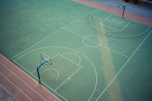 Wuhan, China – October 16, 2022: An outdoor basketball court with a vibrant green playing surface, populated by athletes playing the sport