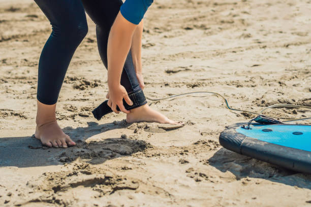 istock Summer time and active rest concept. Young surfer woman beginner fastens leash across leg, going to surf on big barral waves on ocean, dresseed in boardies, poses aganist sky on hot sunny day 1086193744