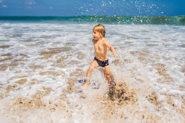istock boy playing on the beach in the water 1086197552