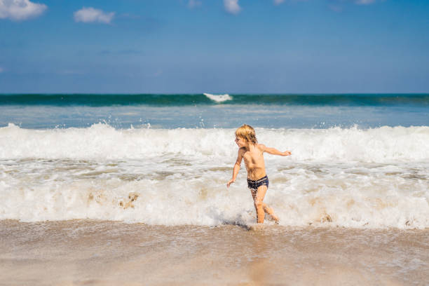 istock boy playing on the beach in the water 1086197556