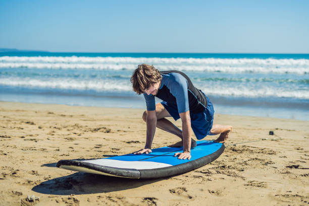 istock Young man surfer training before go to lineup on a sand beach. Learning to surf. Vacation concept. Summer holidays. Tourism, sport 1086199488