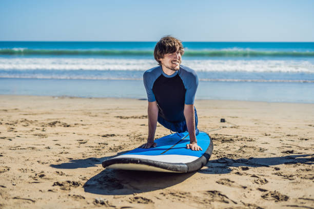 istock Young man surfer training before go to lineup on a sand beach. Learning to surf. Vacation concept. Summer holidays. Tourism, sport 1086199490