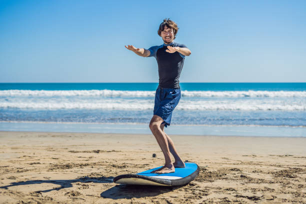 istock Young man surfer training before go to lineup on a sand beach. Learning to surf. Vacation concept. Summer holidays. Tourism, sport 1086199506