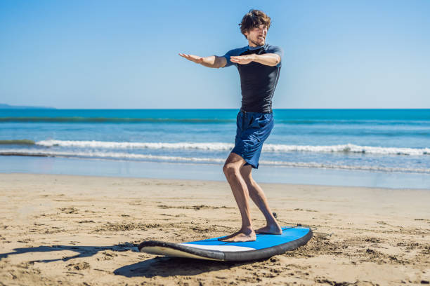 istock Young man surfer training before go to lineup on a sand beach. Learning to surf. Vacation concept. Summer holidays. Tourism, sport 1086199508