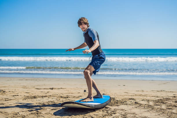 istock Young man surfer training before go to lineup on a sand beach. Learning to surf. Vacation concept. Summer holidays. Tourism, sport 1086199514