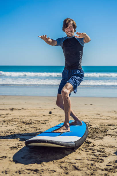 istock Young man surfer training before go to lineup on a sand beach. Learning to surf. Vacation concept. Summer holidays. Tourism, sport 1086199540