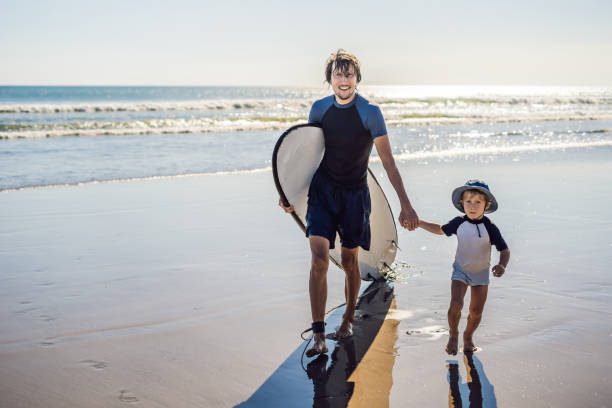 istock Father and son surfers have a good time on the beach 1086199580