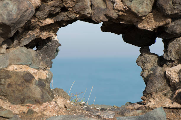 View of blue sea from hole window frame in wall