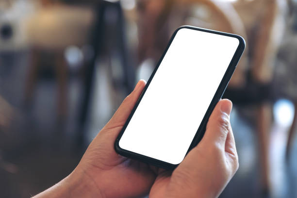 istock Mockup image of hands holding black mobile phone with blank white desktop screen in cafe 1086218214