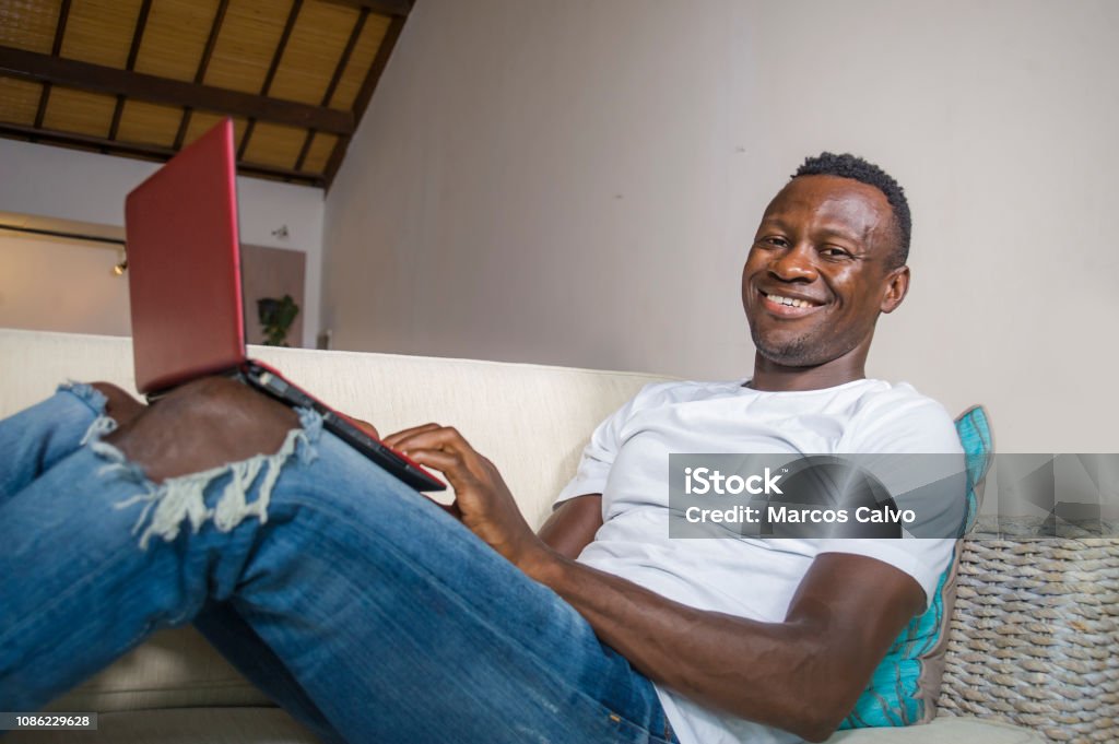 young attractive and happy successful black afro American man networking with laptop computer at living room couch smiling cheerful and satisfied in internet business success concept 30-39 Years Stock Photo